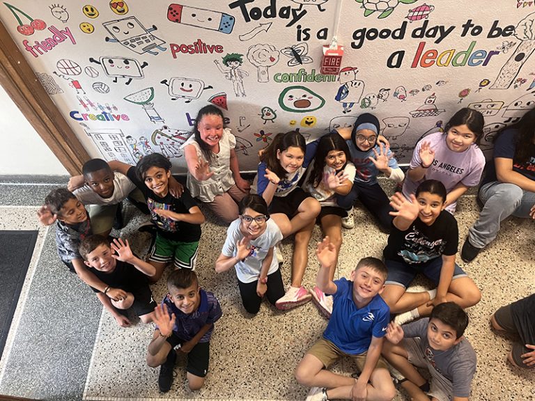 A group of students in front of a mural they are creating as part of the 2024 Summer Discovery Program at Lindbergh Elementary.